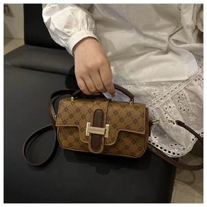 Detail of the elegant floral printed brown leather handbag with golden metal lock and strap