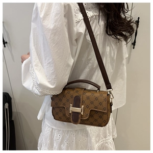Detail of brown monogram shoulder bag with metallic H buckle on white lace shirt