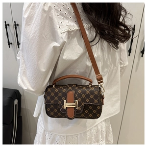 Close-up of luxury dark brown monogram handbag with golden H buckle and caramel handle