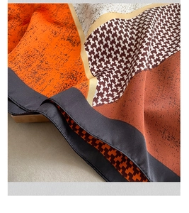 Close-up of geometric color block silk scarf with orange houndstooth pattern and fine edges
