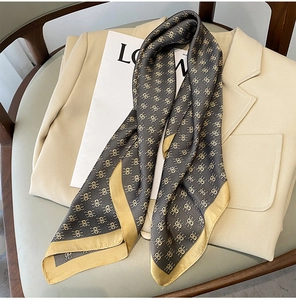 Macro view of silk-textured scarf with golden geometric patterns on grey suit