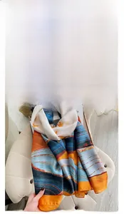 Detail of silk-like scarf featuring blue wave patterns and vibrant orange contrast design