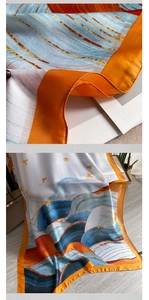 Detail of silk scarf showing orange edges and abstract wave pattern with gold birds
