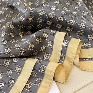 Close-up of silk-like blue scarf showing gold pattern texture and premium glossy finish