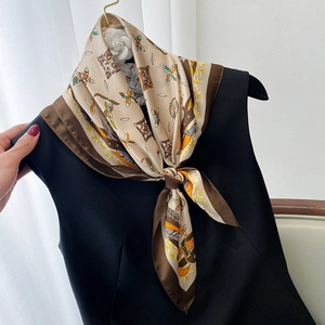Detail view of champagne silk scarf with vintage equestrian buckle pattern tied on a dress