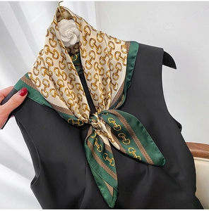 Close-up of equestrian print silk scarf with golden buckles on a black vest
