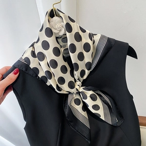 Close-up of a black and white polka dot satin scarf tied in a bow on a black dress