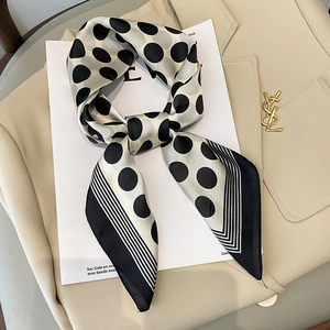 Elegant silk-like square scarf featuring classic polka dots and striped edges on a blazer