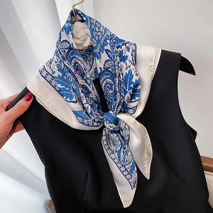 Close-up of paisley silk scarf styled on dress with a camellia flower brooch