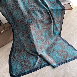 Blue and brown paisley satin scarf displayed elegantly on a light wooden background