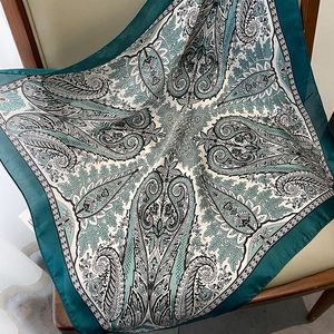 Detail of vintage paisley silk scarf with dark teal border on a minimalist chair