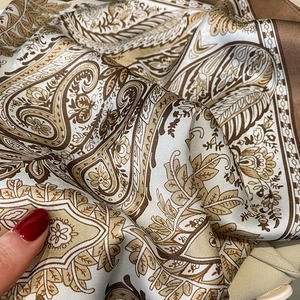 Detailed macro view of paisley floral faux silk scarf with elegant champagne and brown tones