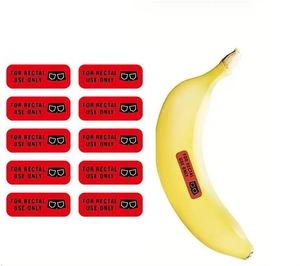 Vue détaillée d'autocollants humoristiques rectaux appliqués sur une banane pour l'échelle
