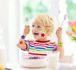 Jeune enfant appliquant des autocollants étoiles pailletées à smiley sur le bras