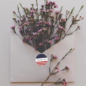 Close-up of circular US flag stickers with Thank You text on a white envelope gift
