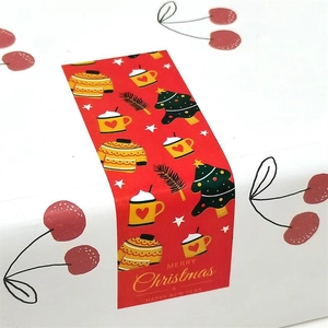 Close-up of red Christmas sweater and tree gift stickers on white cardboard box