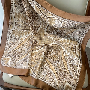 Detail of paisley floral silk scarf showing premium texture on a wooden chair