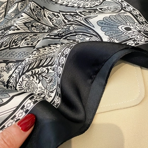 Macro shot of paisley pattern silk scarf with satin finish and broad black border edges