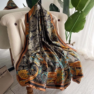 Retro paisley silk-like scarf with gold and blue patterns draped on a beige sofa
