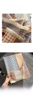 Detail of cashmere-feel scarf with houndstooth pattern and golden tassel fringe edges
