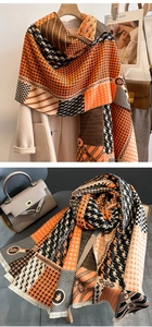Detail of cashmere-like scarf with houndstooth pattern, orange-black color block, and fringe
