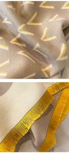 Detail showing the khaki knit scarf texture with yellow fringe and V-shaped patterns