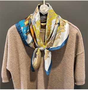 Close-up of silk neck scarf with artistic print tied on a brown sweater with camellia