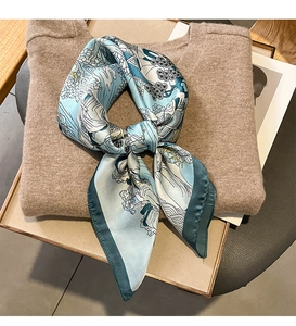 Close-up of silk scarf with blue-green Ukiyo-e waves tied over a beige knit sweater