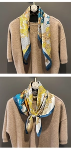 Detail of printed silk scarf with blue and yellow nature patterns tied on a sweater