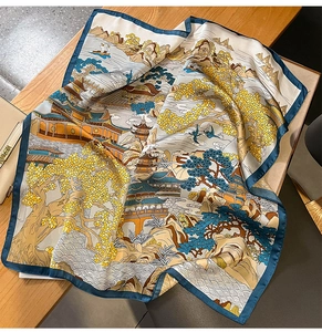 Detail of silk square scarf featuring traditional landscape print on a wooden table