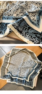 Details des Satin-Halstuchs mit blauem Leopardenmuster und geometrischen Streifen