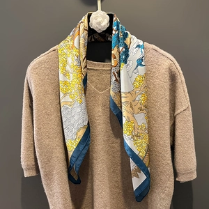 Elegant silk scarf with yellow and blue tree patterns on a camel knit sweater