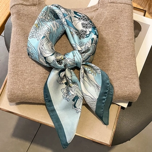 Elegant silk-like square scarf with blue illustrated print on a warm knit background