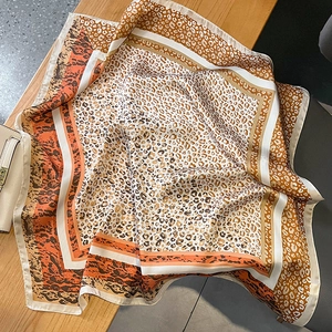 Eleganter Seidenschal mit Leopardenmuster in Orange und Braun auf einer Holzoberfläche