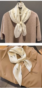 Close-up of cream faux silk scarf with black bird print styled on a knitted sweater