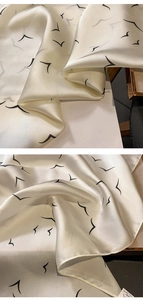 Detail of cream silk scarf featuring minimalist black bird print and rolled edges