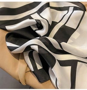 Detail of silk-like scarf featuring black and white geometric patterns on fabric
