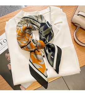 Detail of printed satin scarf with leaf patterns styled on a white collared shirt