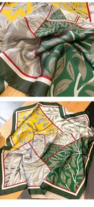 Detailed close-up of patterned silk scarf with abstract leaves in green and yellow