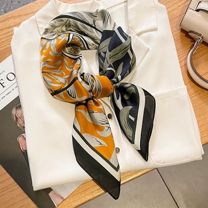 Elegant orange and navy leaf print silk-like scarf tied on a white shirt collar