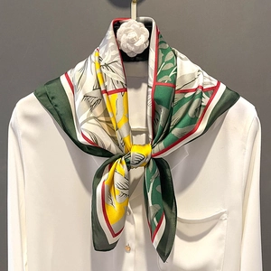 Elegant printed satin square scarf in green and yellow draped on a white shirt collar