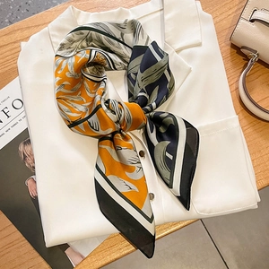 Elegant tropical leaf print silk scarf in orange and green tied on a white shirt