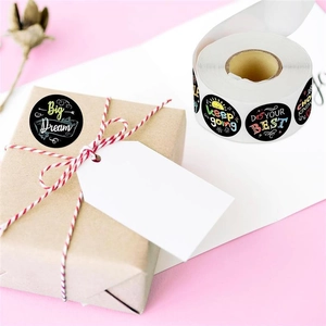 Roll of black round stickers with colorful motivational quotes on a gift box background