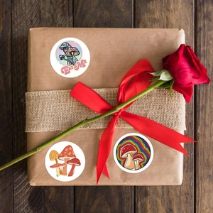 Detail of colorful mushroom stickers with Eat Me text on kraft gift box with red roses