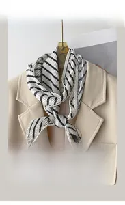 Close-up of pleated black and white striped scarf on a beige blazer and wooden hanger