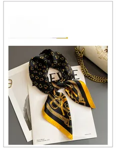 Close-up of silk square scarf with golden equestrian motifs and yellow border on a magazine