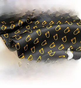 Macro shot of luxury black mulberry silk scarf featuring golden chain pattern details