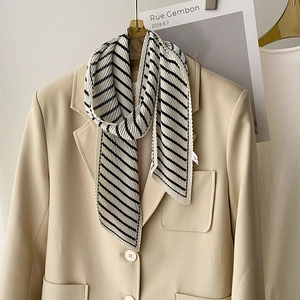 Close-up of black and white striped pleated scarf styled on a beige blazer lapel
