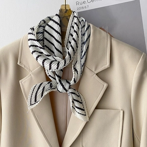 Close-up of pleated black and white striped scarf with elegant texture on beige suit