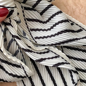 Detail shot of pleated striped scarf showing premium texture and fine accordion folds